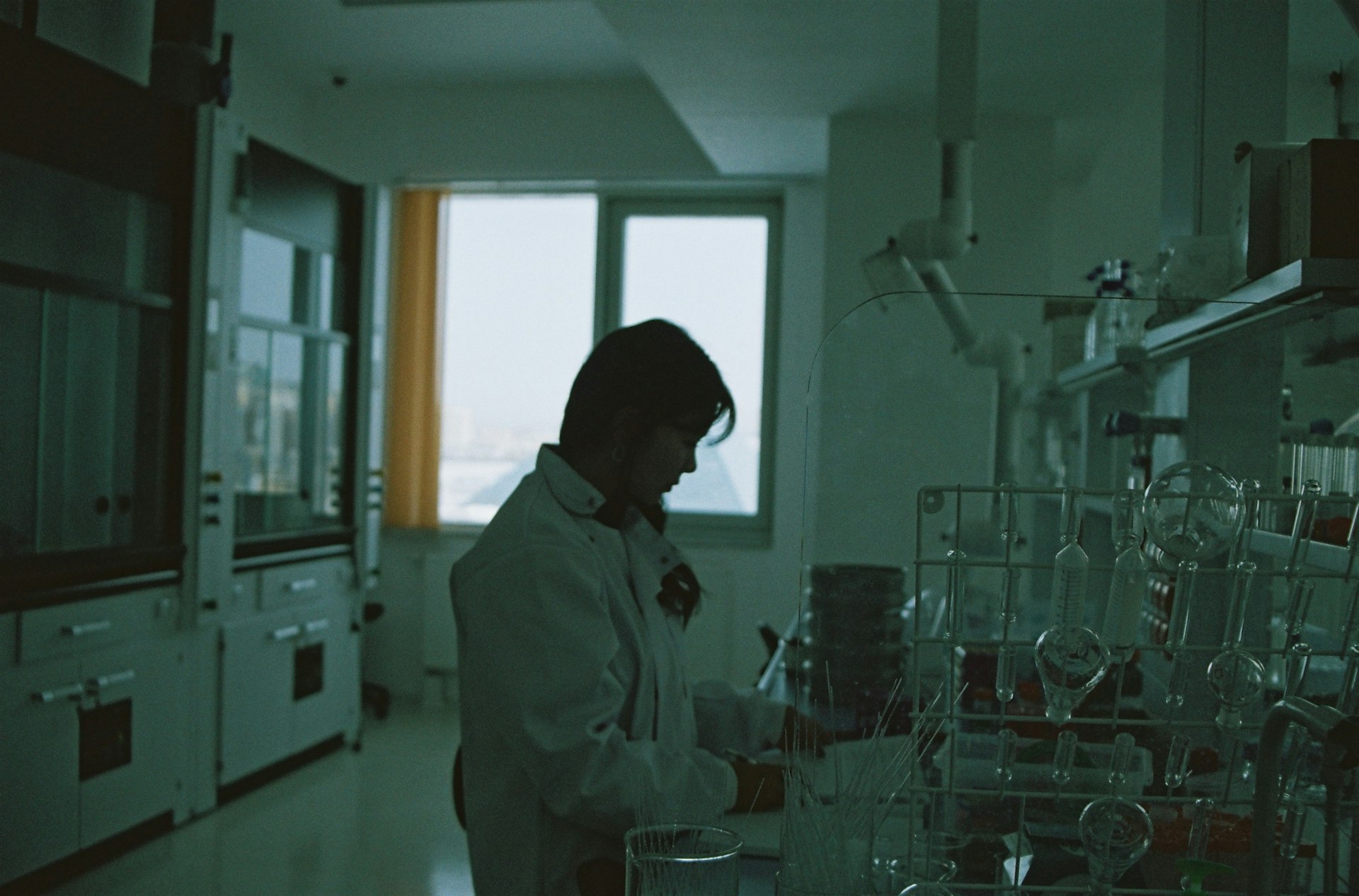 man in white dress shirt standing near window working on a chemical solution